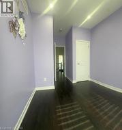 Dark wood-finish flooring with white baseboards, recessed ceiling lighting, and a white interior door - 