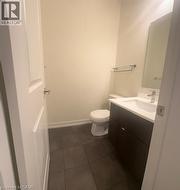 Dark-toned floor tiles, a modern vanity with integrated sink, and a wall-mounted mirror - 