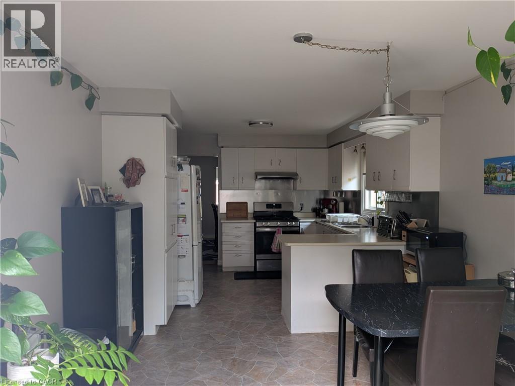 Kitchen featuring light-toned cabinetry, stainless steel range with overhead hood, and a peninsula countertop - 45 Caswell Drive Unit# Upper, Hamilton, ON - Indoor