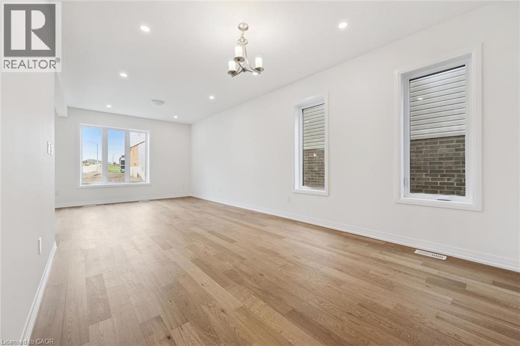 Spacious room featuring wood-finish flooring, recessed lighting, and a contemporary chandelier - 451 Benninger Street, Kitchener, ON