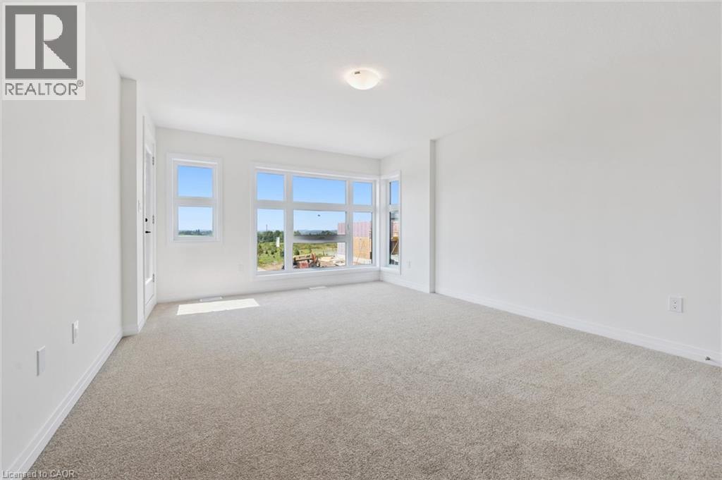 Neutral tone wall paint, light-colored carpeting, multiple windows, and a ceiling-mounted light fixture - 451 Benninger Street, Kitchener, ON