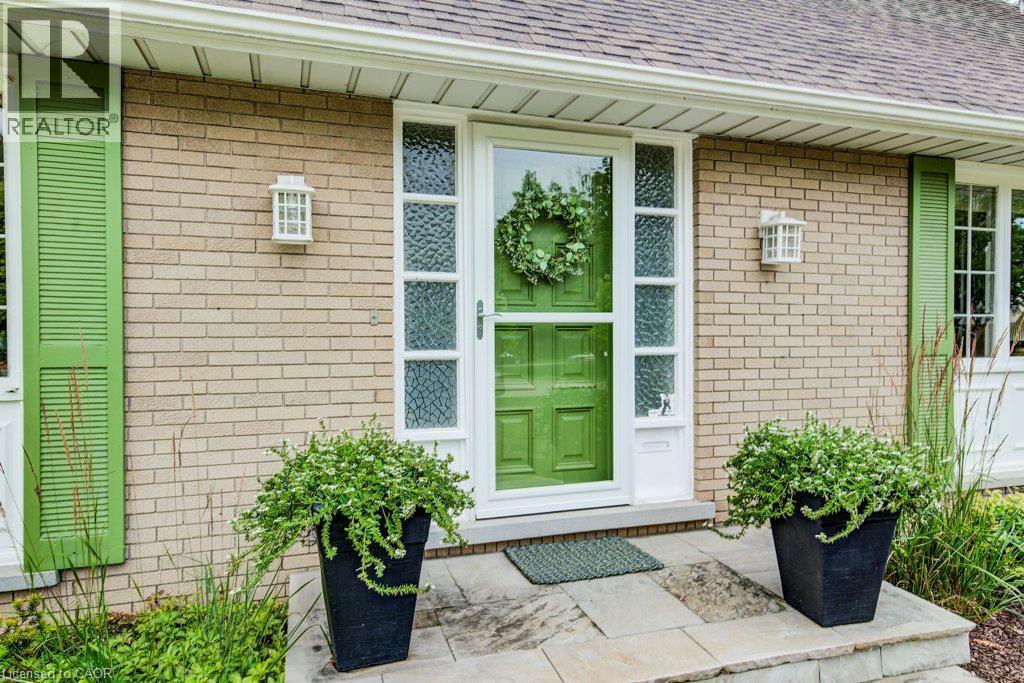 Brick exterior featuring a vibrant green entry door with a storm door, flanked by decorative sidelights and green louvered shutters - 97 Somerset Crescent, Waterloo, ON - Outdoor With Exterior