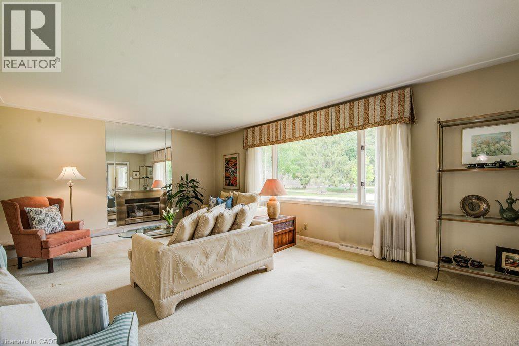 Spacious living area featuring a large picture window, a built-in fireplace with a mirrored surround, and wall-to-wall carpeting - 97 Somerset Crescent, Waterloo, ON - Indoor Photo Showing Living Room
