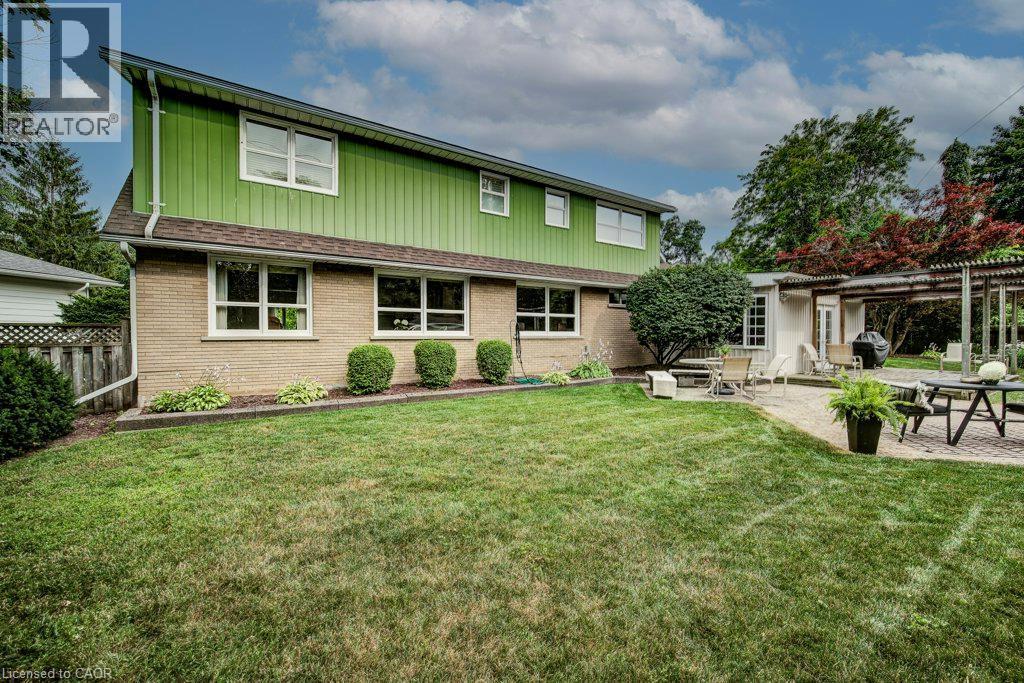 Expansive grassy yard area with a paved patio featuring a pergola - 97 Somerset Crescent, Waterloo, ON - Outdoor