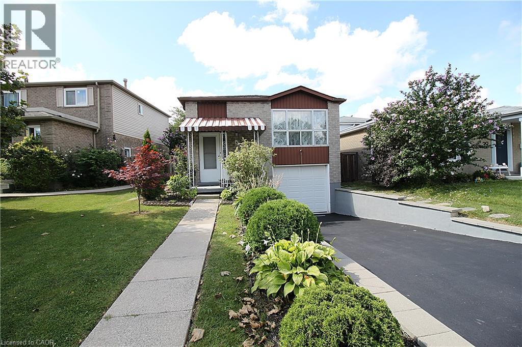 Brick exterior with a peaked roofline, front awning, attached garage, and a paved driveway - 35 Garden Crescent, Hamilton, ON - Outdoor