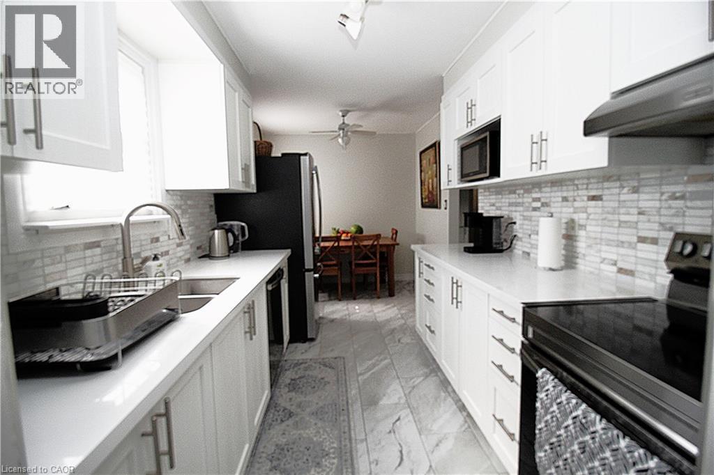 Galley kitchen with white shaker-style cabinetry, stainless steel sink, and light-toned countertops - 35 Garden Crescent, Hamilton, ON - Indoor Photo Showing Kitchen With Upgraded Kitchen