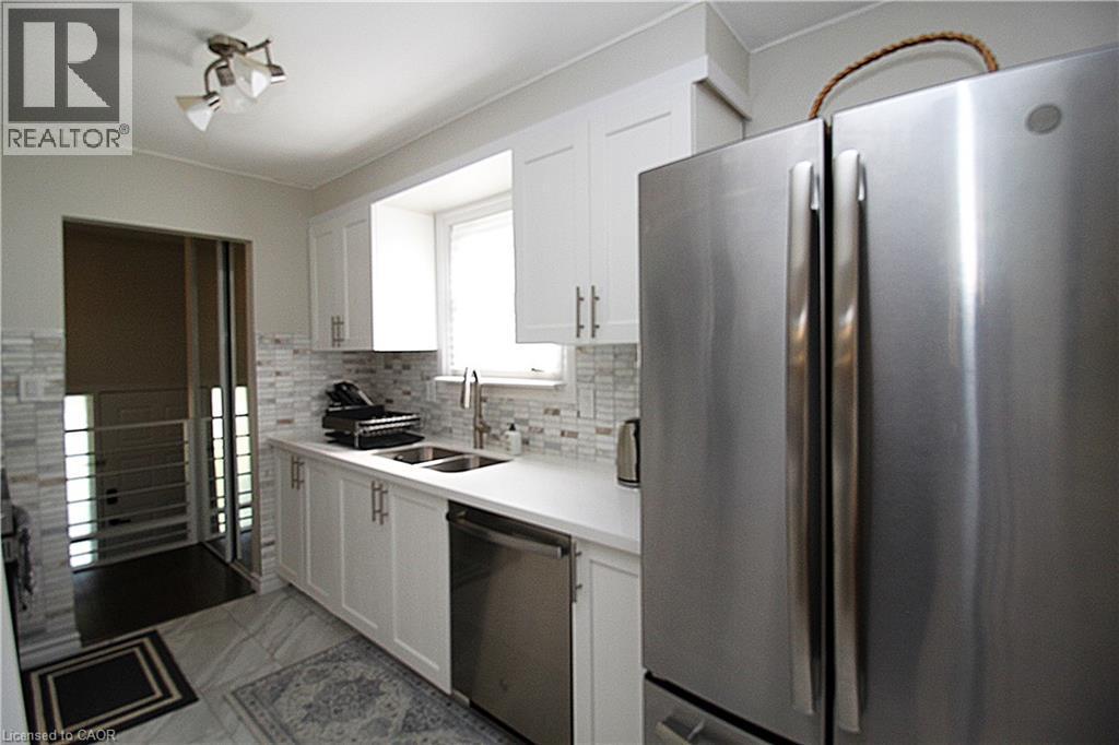 White cabinetry, stainless steel appliances, mosaic tile backsplash, double basin sink, and recessed lighting - 35 Garden Crescent, Hamilton, ON - Indoor Photo Showing Kitchen With Double Sink