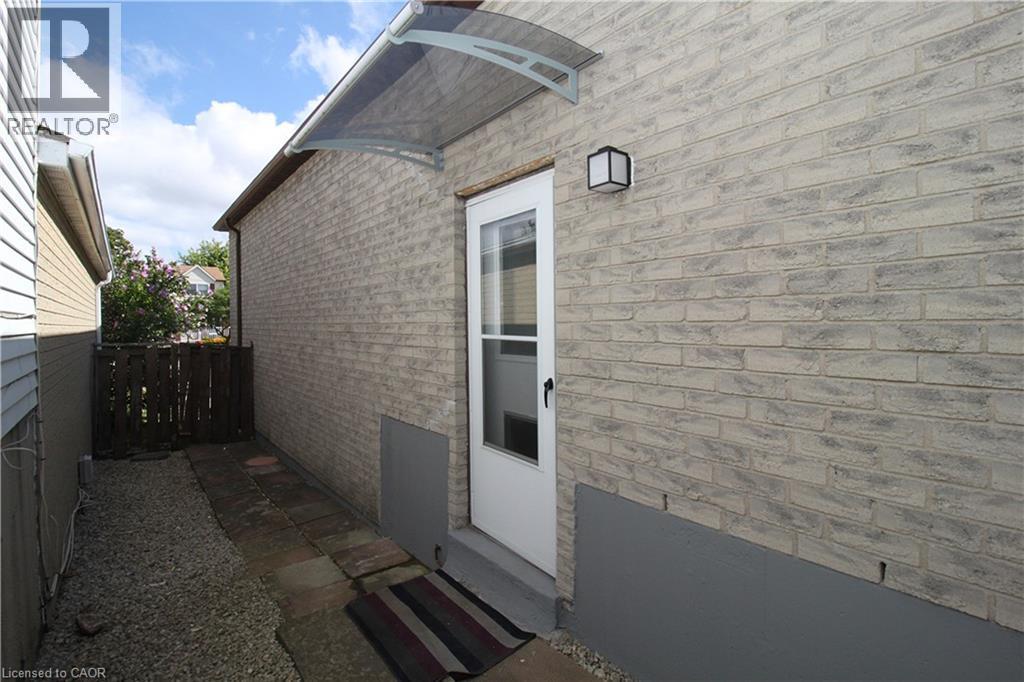 Brick exterior with a clear entry awning, exterior wall light, and a glass-paneled door - 35 Garden Crescent, Hamilton, ON - Outdoor With Exterior