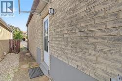 Brick exterior with white door, outdoor lighting fixture, clear awning, and partial paver pathway - 