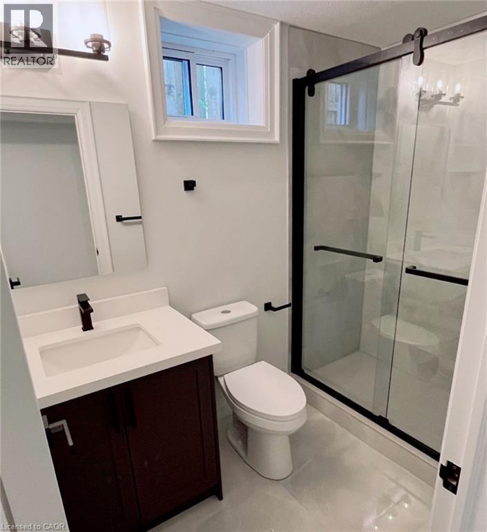 Vanity with a white countertop and integrated sink, matte black faucet, and dark wood-finish cabinetry - 81 Second Avenue Unit# B, Kitchener, ON - Indoor Photo Showing Bathroom