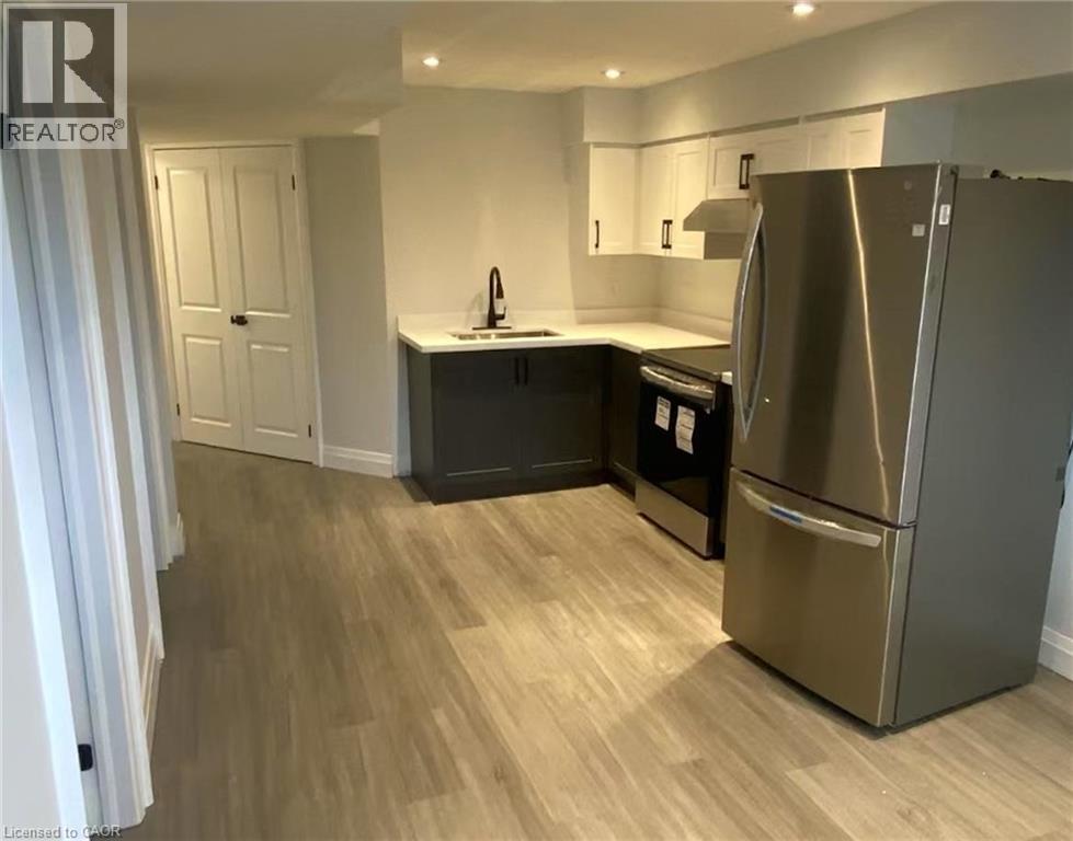 Kitchenette featuring stainless steel appliances, wood-finish flooring, white upper cabinetry, dark lower cabinetry, and recessed lighting - 81 Second Avenue Unit# B, Kitchener, ON - Indoor Photo Showing Kitchen