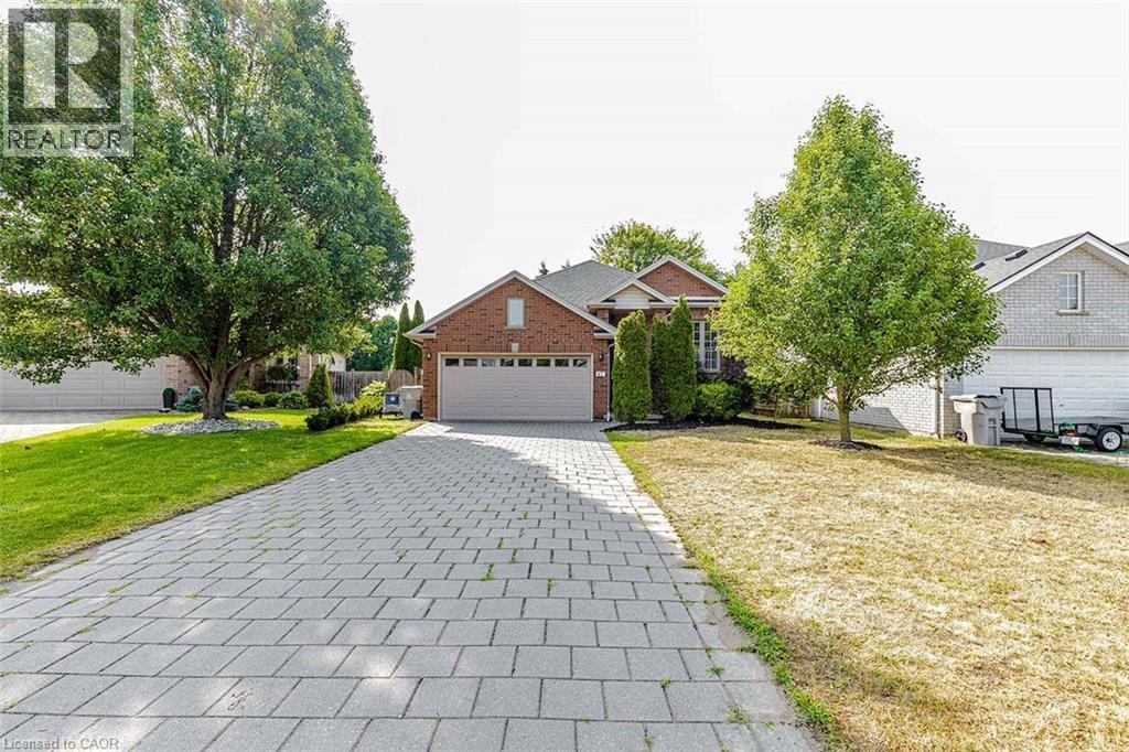 Brick exterior featuring a paver driveway, attached garage, and mature trees - 47 Queensway Drive, Strathroy, ON - Outdoor