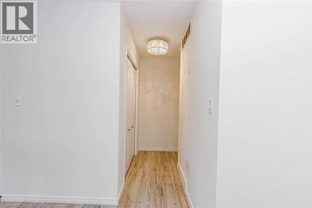Hallway featuring wood-finish flooring, white walls, and a contemporary ceiling light fixture - 47 Queensway Drive, Strathroy, ON - Indoor Photo Showing Other Room