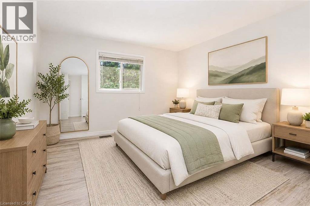 Light-toned wood-finish flooring, neutral wall tones, and a window with exterior foliage - 47 Queensway Drive, Strathroy, ON - Indoor Photo Showing Bedroom