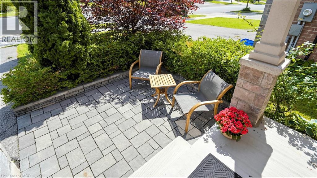 Paver stone patio with a retaining wall, accented by lush landscaping and a stone-clad column - 173 Raymond Road, Ancaster, ON - Outdoor
