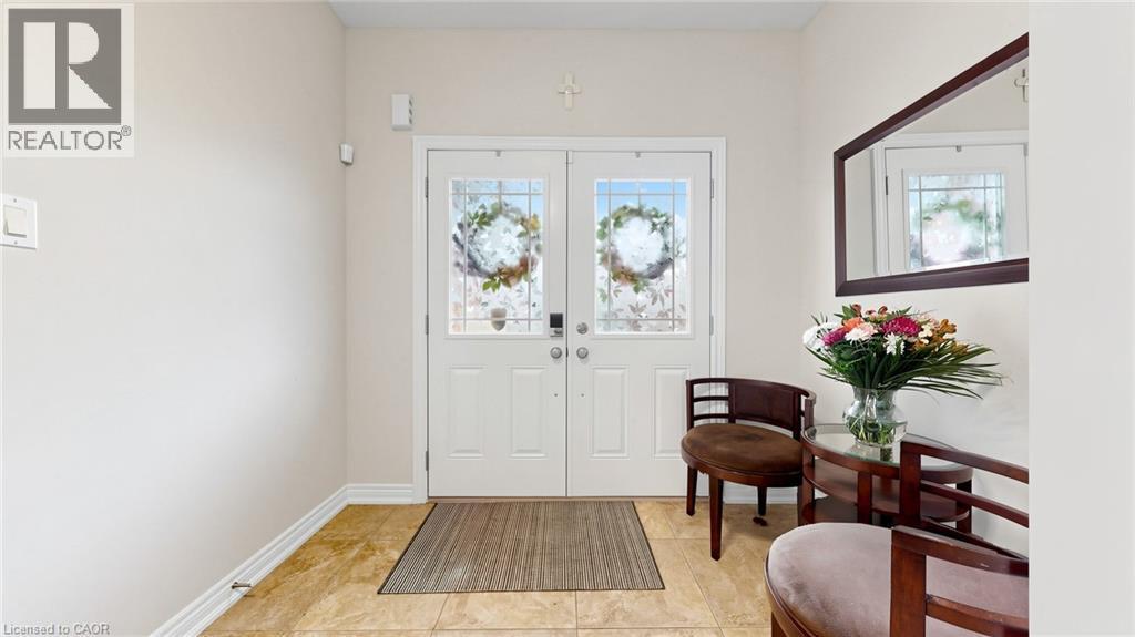 Double entry doors with decorative glass panels, light-toned wall paint, and tiled flooring - 173 Raymond Road, Ancaster, ON - Indoor Photo Showing Other Room