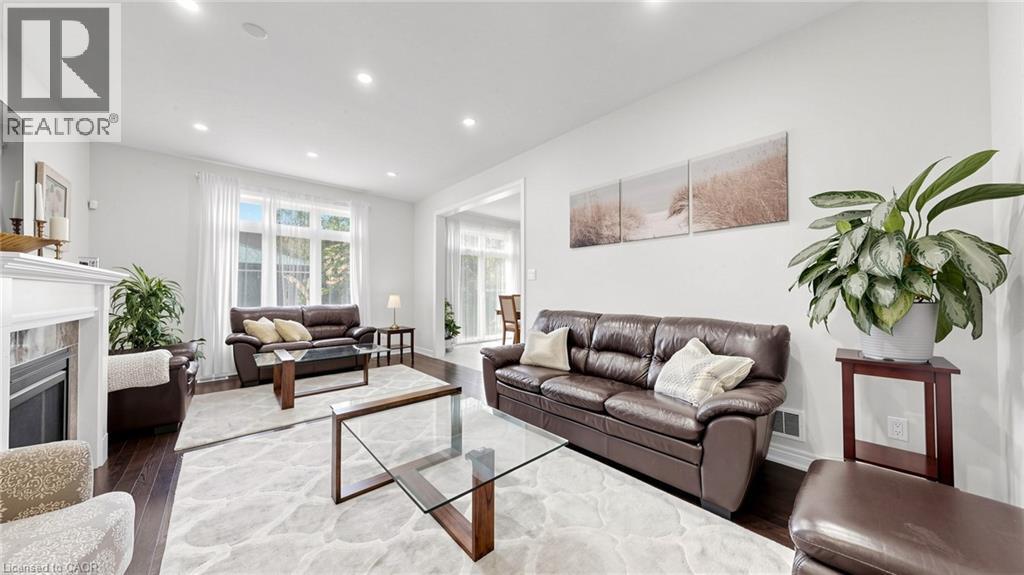Hardwood flooring, recessed lighting, white walls, and a fireplace with a white mantel and tile surround - 173 Raymond Road, Ancaster, ON - Indoor Photo Showing Living Room With Fireplace