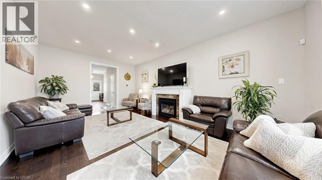 Recessed lighting, wood-finish flooring, and a fireplace with a mantel and stone surround - 173 Raymond Road, Ancaster, ON - Indoor Photo Showing Living Room With Fireplace