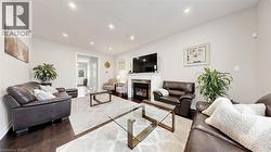 Recessed lighting, wood-finish flooring, and a fireplace with a mantel and stone surround -