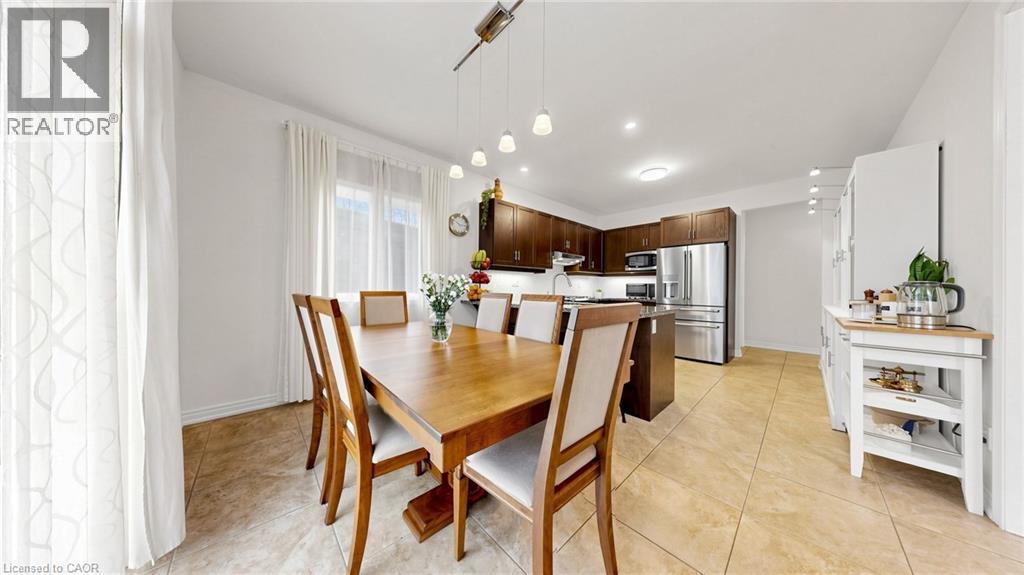 Open concept dining area and kitchen featuring ceramic tile flooring, dark wood cabinetry, stainless steel appliances, and recessed lighting - 173 Raymond Road, Ancaster, ON - Indoor Photo Showing Dining Room