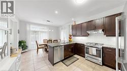 Kitchen featuring dark wood cabinetry, stainless steel appliances, light-toned hexagon tile backsplash, and light-toned granite countertops -