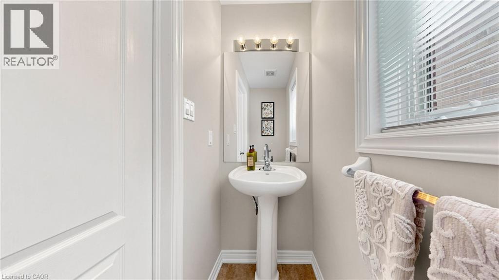 Pedestal sink with chrome faucet, wall-mounted mirror, and vanity light fixture - 173 Raymond Road, Ancaster, ON - Indoor Photo Showing Bathroom