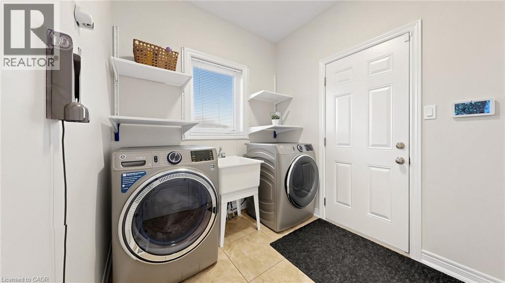 Laundry area featuring tiled flooring, a utility sink, and a window with blinds - 173 Raymond Road, Ancaster, ON - Indoor Photo Showing Laundry Room