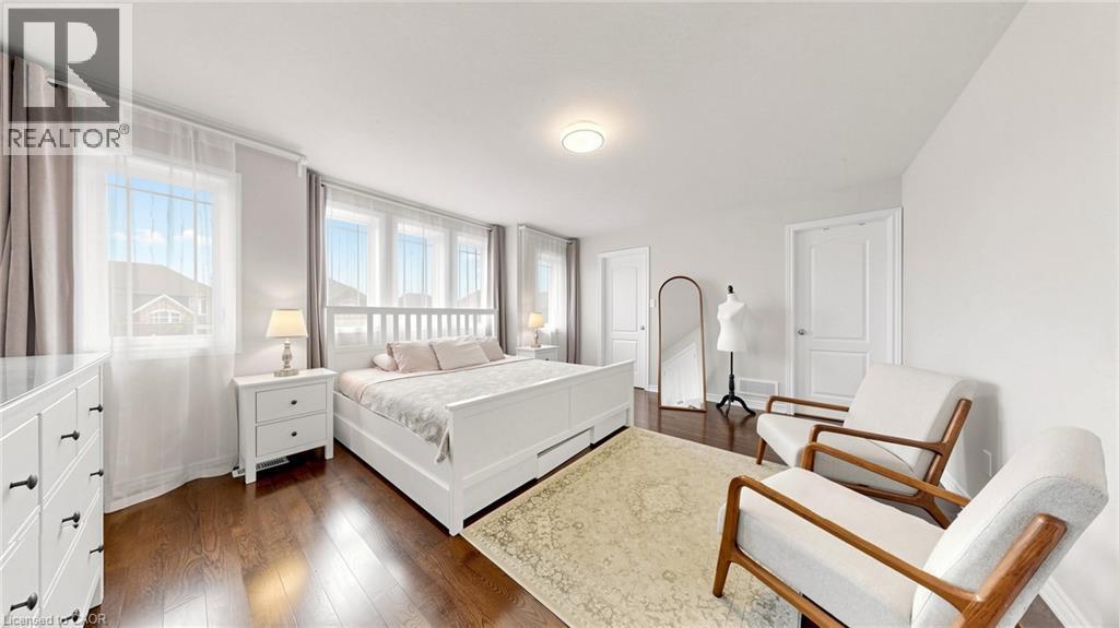 Bright room featuring multiple windows, dark wood-finish flooring, and white walls - 173 Raymond Road, Ancaster, ON - Indoor Photo Showing Bedroom