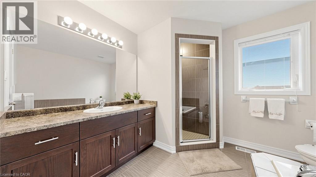 Dark wood-finish vanity with ample storage, a single basin sink, and an expansive mirror - 173 Raymond Road, Ancaster, ON - Indoor Photo Showing Bathroom