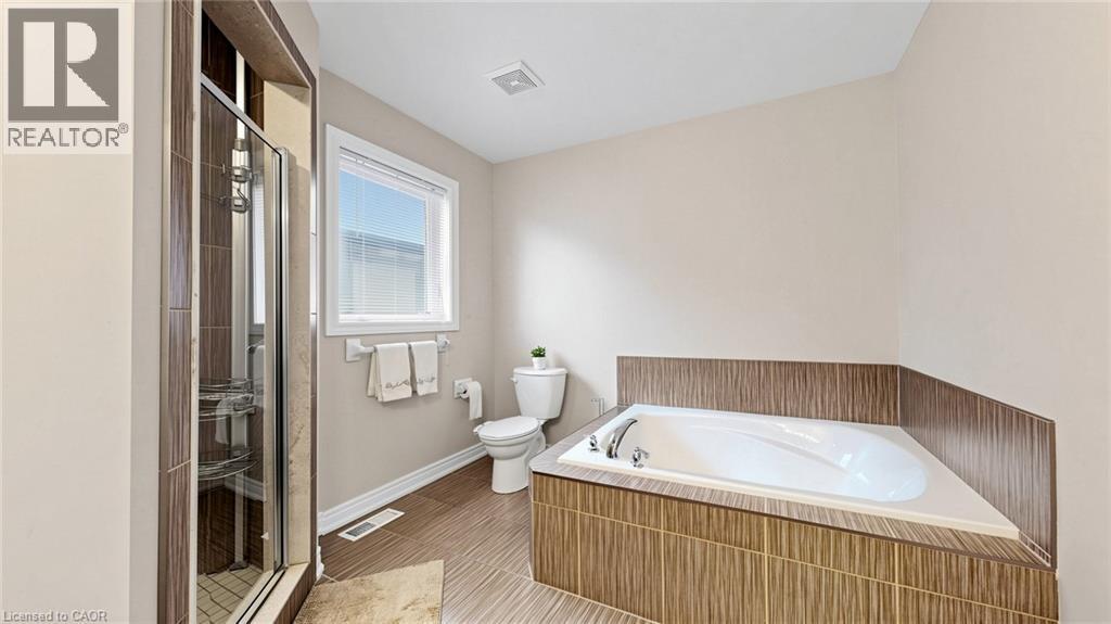 Built-in corner soaking tub with tile surround, glass-enclosed shower with tile, and a window with privacy blinds - 173 Raymond Road, Ancaster, ON - Indoor Photo Showing Bathroom