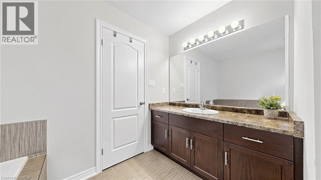 Dual-paneled interior door, expansive vanity with a brown finish, integrated single basin sink, speckled countertop, and wall-mounted strip lighting - 173 Raymond Road, Ancaster, ON - Indoor Photo Showing Bathroom
