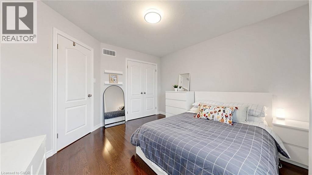 Rich wood-finish flooring, white walls, two paneled doors, and a ceiling-mounted light fixture - 173 Raymond Road, Ancaster, ON - Indoor Photo Showing Bedroom