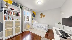Rich wood-finish flooring, built-in shelving, window with sheer and blackout curtains, and a ceiling-mounted light fixture -