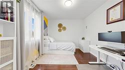 Hardwood flooring, white walls, built-in shelving, large window, and overhead lighting -