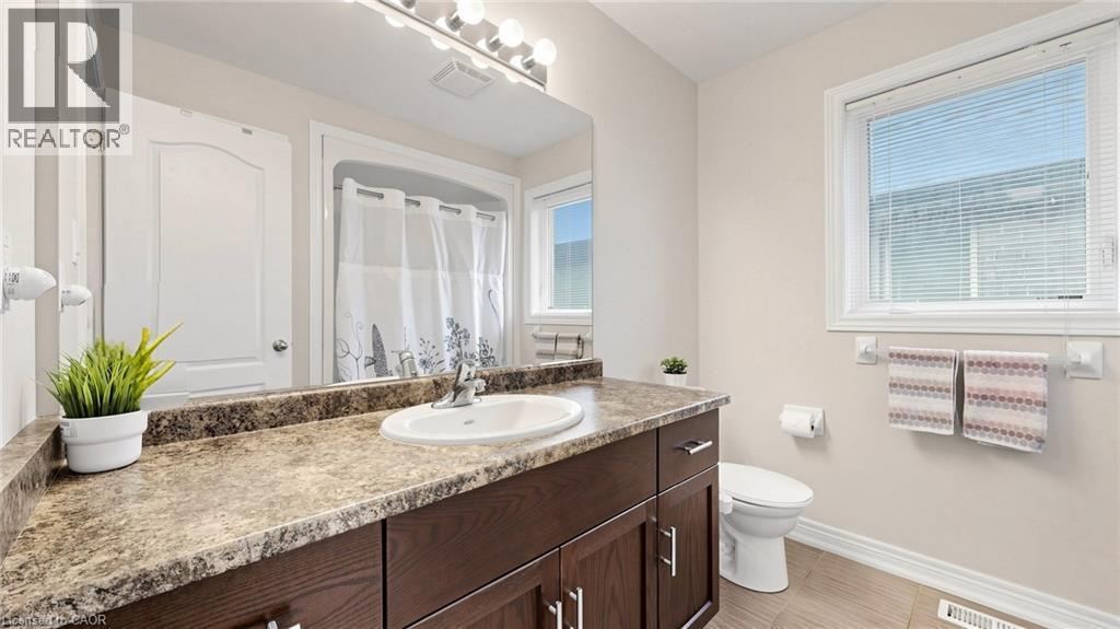 Bathroom featuring a single vanity with wood-finish cabinetry, a broad mirror, overhead bar lighting, and a shower/tub combination - 173 Raymond Road, Ancaster, ON - Indoor Photo Showing Bathroom