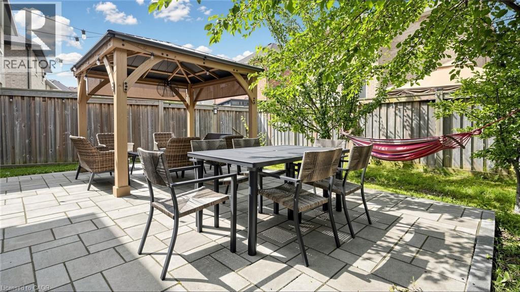 Paved patio with a wood gazebo, surrounded by a wood fence, and mature trees - 173 Raymond Road, Ancaster, ON - Outdoor With Deck Patio Veranda