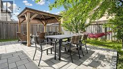 Paved patio with a wood gazebo, surrounded by a wood fence, and mature trees -
