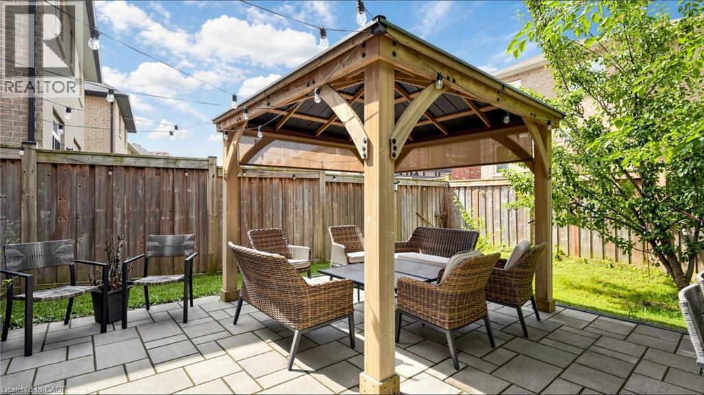 Stone paver patio with a wood gazebo, string lighting, and a wood fence enclosure - 173 Raymond Road, Ancaster, ON - Outdoor With Deck Patio Veranda