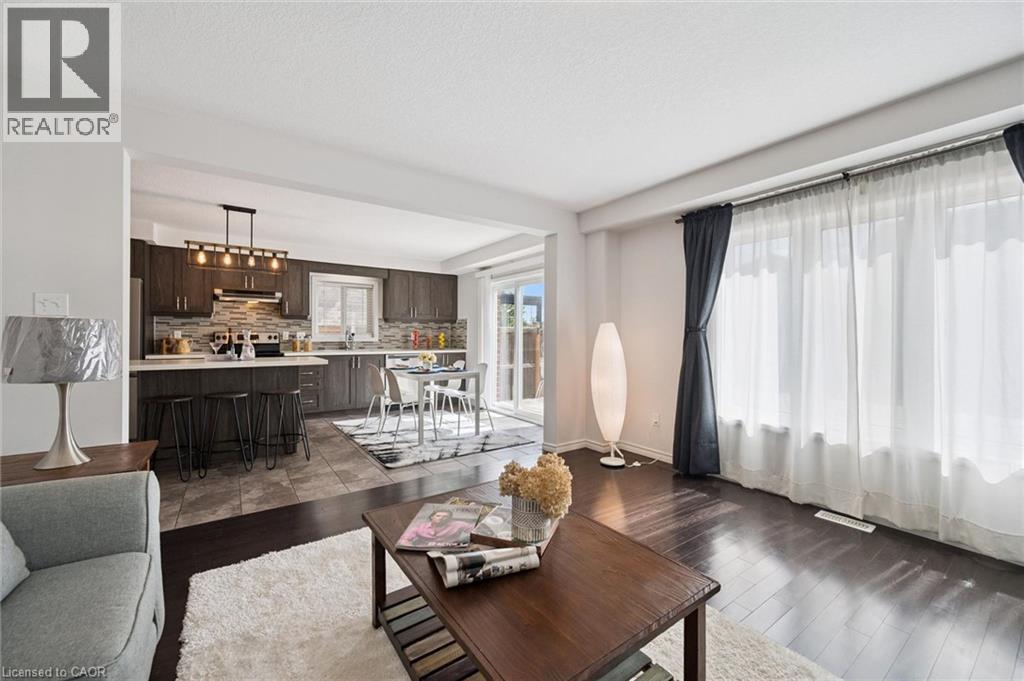 Open concept design with dark wood-finish flooring, a kitchen featuring dark wood cabinetry, a light-colored countertop, and a tile backsplash, and a dining area with direct access to an outdoor space - 360 Freure Drive, Cambridge, ON - Indoor Photo Showing Living Room
