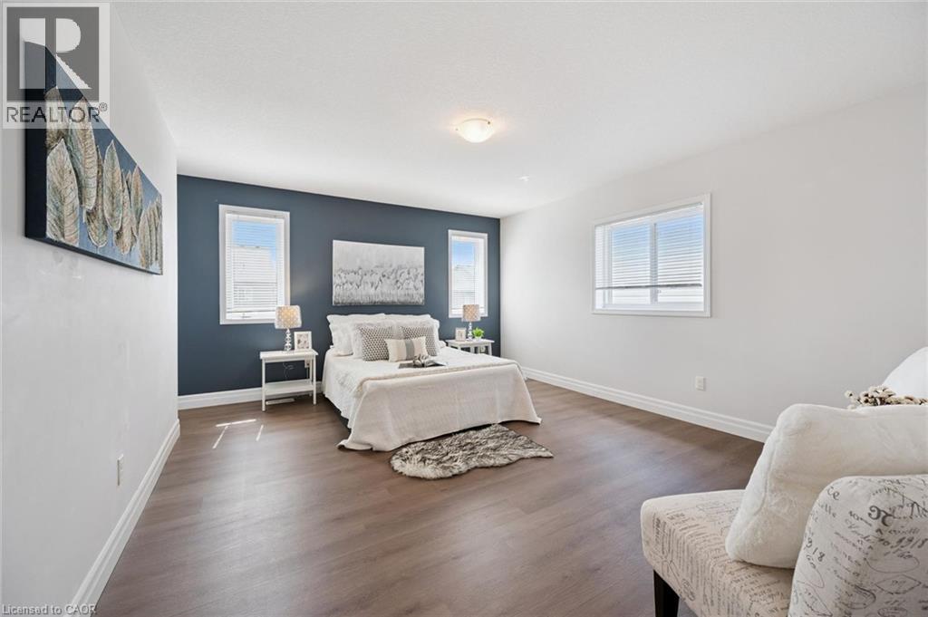 Wood-finish flooring, white walls, and a contrasting accent wall with two windows - 360 Freure Drive, Cambridge, ON - Indoor Photo Showing Bedroom