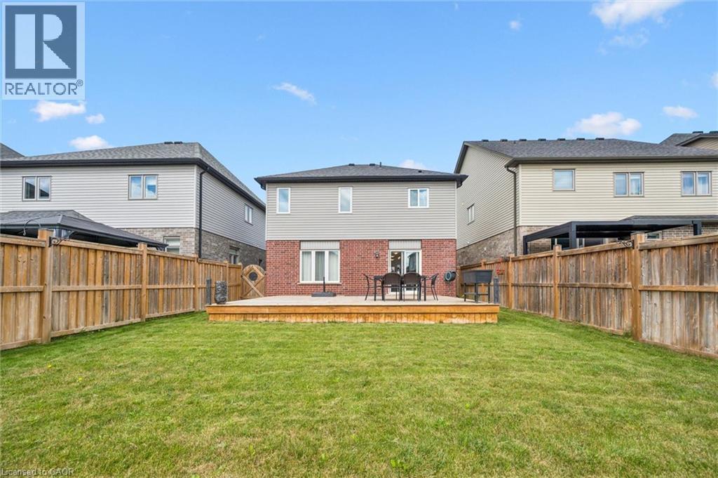Expansive backyard featuring a manicured lawn, full wood fencing, and a raised wood deck - 360 Freure Drive, Cambridge, ON - Outdoor With Deck Patio Veranda With Exterior