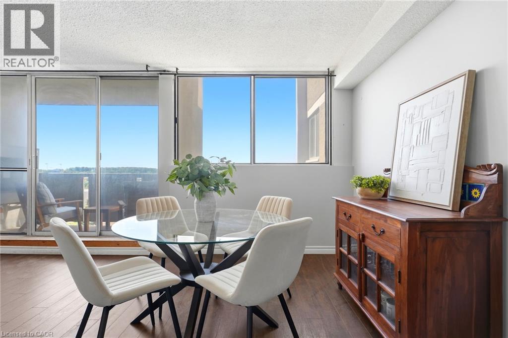 Wood-finish flooring throughout, bright interiors with large windows, and a glass-paneled sliding door opening to an outdoor space - 375 King Street N Unit# 708, Waterloo, ON - Indoor Photo Showing Dining Room