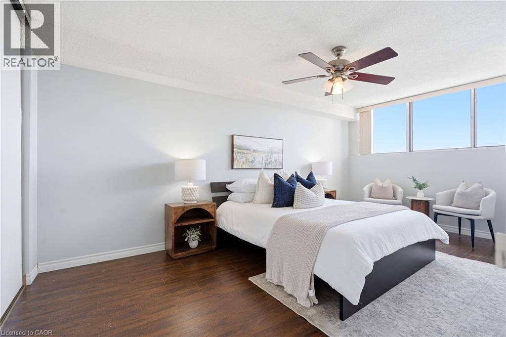 Wood-finish flooring with a light-toned ceiling, featuring a ceiling fan with integrated lighting - 375 King Street N Unit# 708, Waterloo, ON - Indoor Photo Showing Bedroom