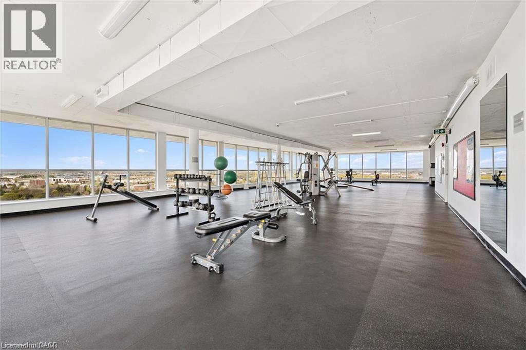 Spacious fitness area featuring floor-to-ceiling windows, soft rubber flooring, and integrated wall mirrors - 375 King Street N Unit# 708, Waterloo, ON - Indoor Photo Showing Gym Room