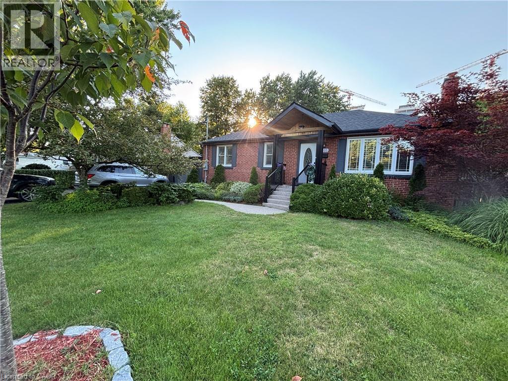 Brick exterior with a dark shingle roof, white trim windows, and a prominent front door - 2105 Maplewood Drive, Burlington, ON - Outdoor