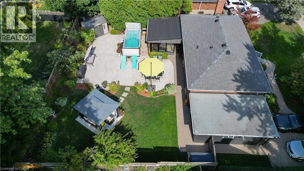Expansive backyard featuring a concrete patio, a built-in swimming pool, a dedicated lawn area, a gazebo, and mature landscaping - 2105 Maplewood Drive, Burlington, ON - Outdoor With View