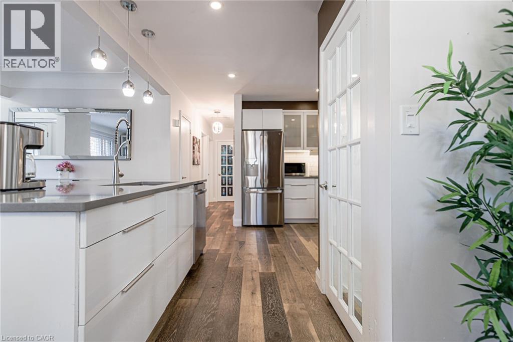 Kitchen featuring a large island with an undermount sink, pendant lighting, recessed lighting, wood-finish flooring, and stainless steel appliances - 2105 Maplewood Drive, Burlington, ON - Indoor Photo Showing Kitchen With Stainless Steel Kitchen With Upgraded Kitchen