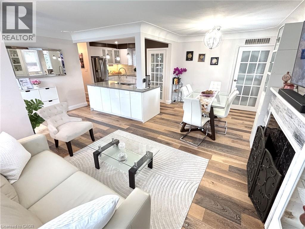 Open-concept living space featuring wood-finish flooring, a kitchen island with stone countertop, and an ornamental fireplace surround - 2105 Maplewood Drive, Burlington, ON - Indoor Photo Showing Living Room