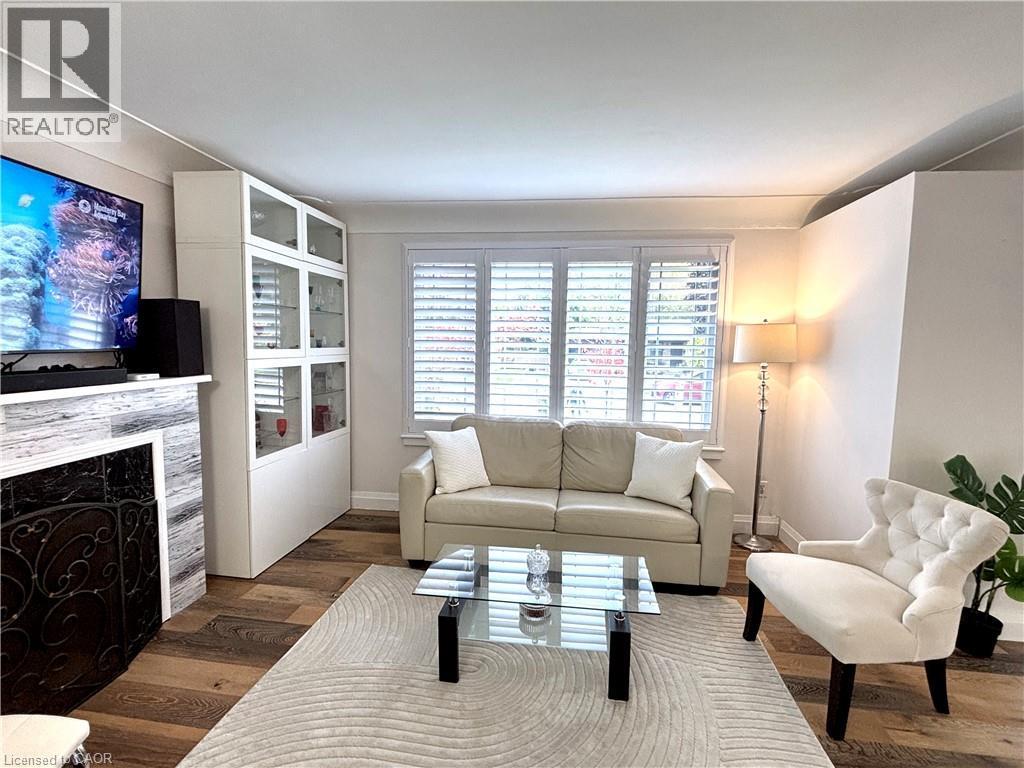 Living area featuring wood-finish flooring, a fireplace with a decorative screen, and a built-in display cabinet - 2105 Maplewood Drive, Burlington, ON - Indoor Photo Showing Living Room With Fireplace