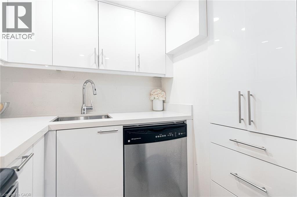 White high-gloss cabinetry, stainless steel sink with gooseneck faucet, integrated dishwasher, and white countertops with matching backsplash - 2105 Maplewood Drive, Burlington, ON - Indoor Photo Showing Kitchen With Double Sink